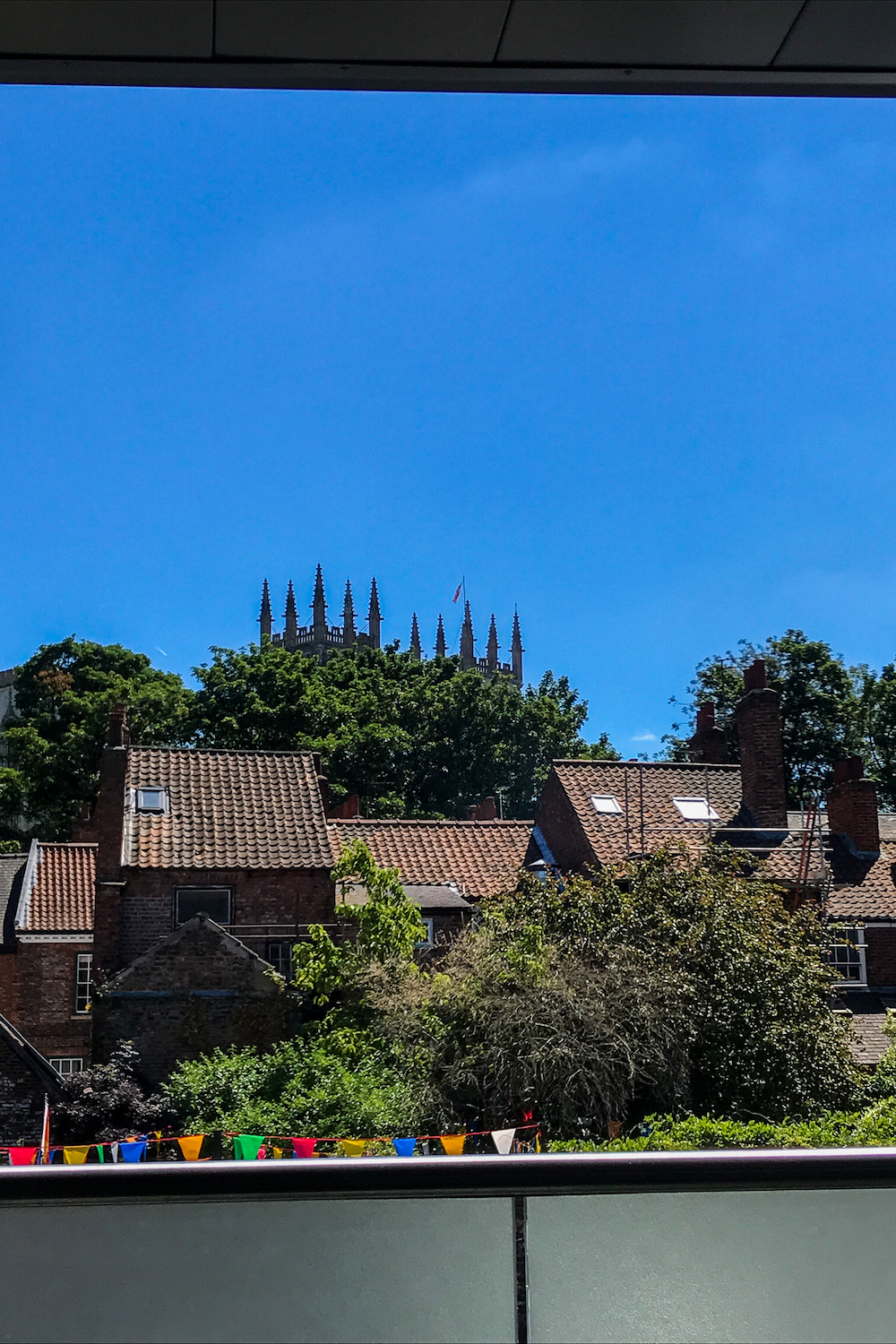 the top of york minster cathedral poking out behind trees