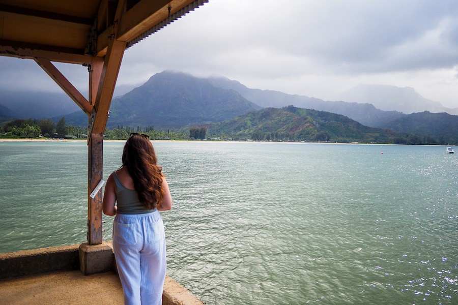 author, a young woman, standing on Hanalei Pier, looking out at the view of the mountains