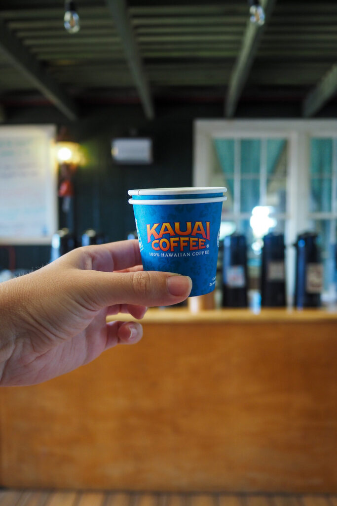 hand holding up a coffee cup that says "Kauai Coffee"
