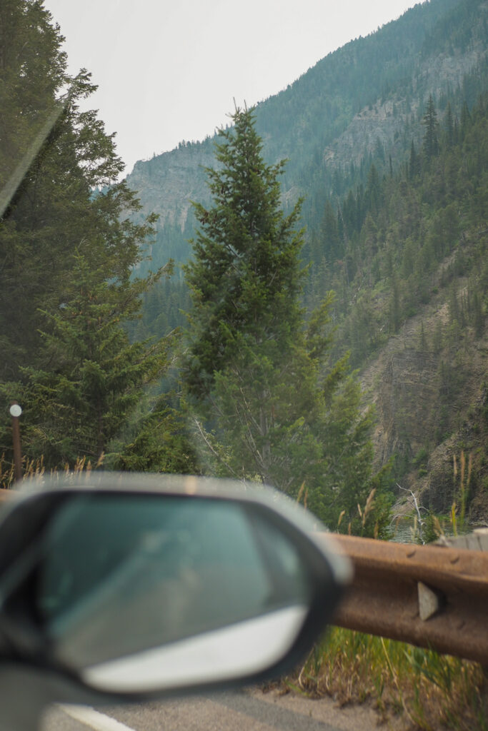 sideview mirror on a car on a road with view of mountains