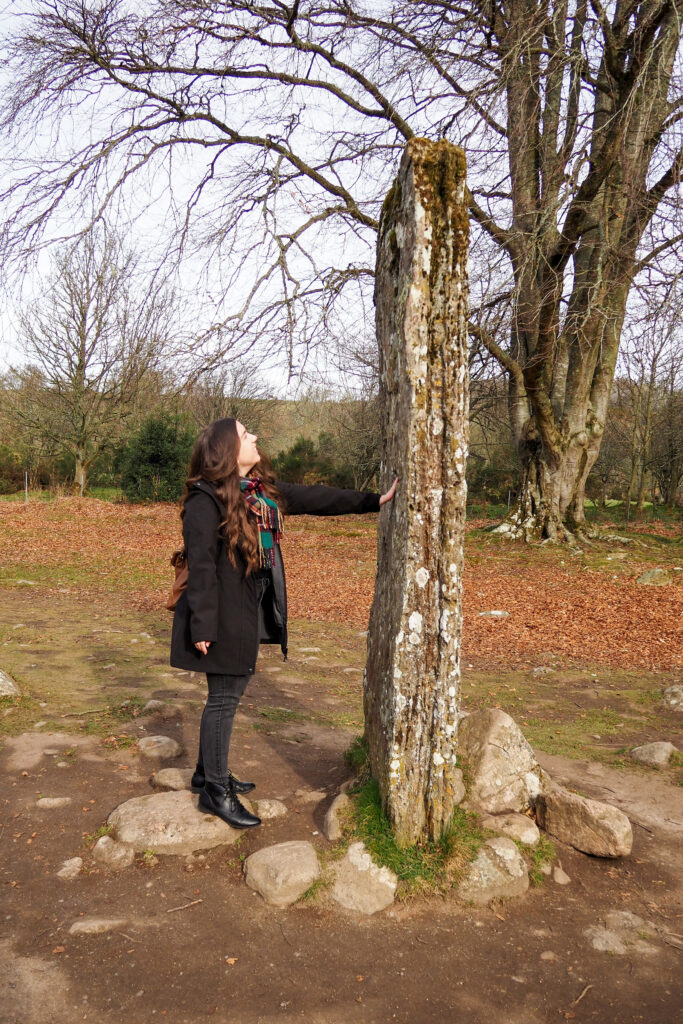 Author touching a stone in a stone circle at Clava Cairns near Inverness, Scotland