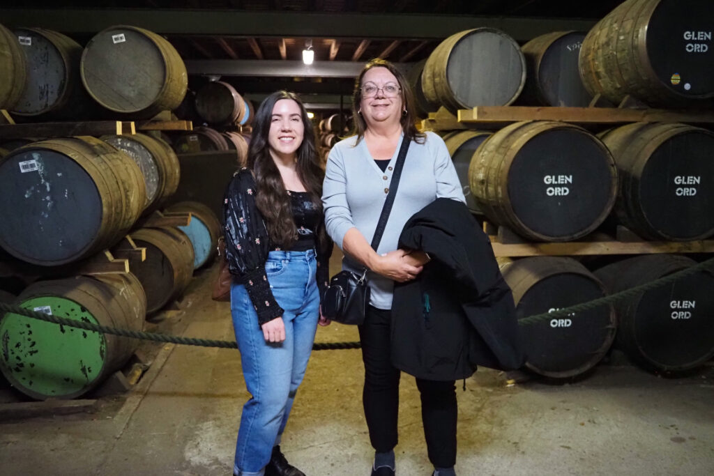 Author and mom next to barrels of whisky at Glen Ord Distillery (The Singleton Distillery) near Inverness, Scotland