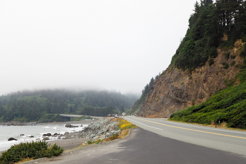 road that goes by the coast and has moody fog all around it