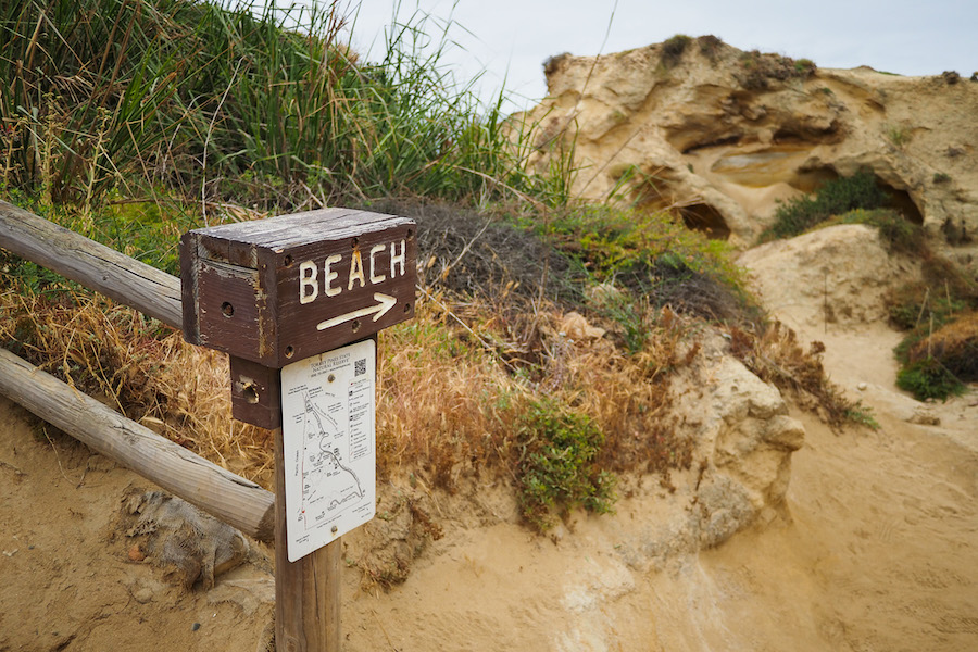 sign that says BEACH with an arrow