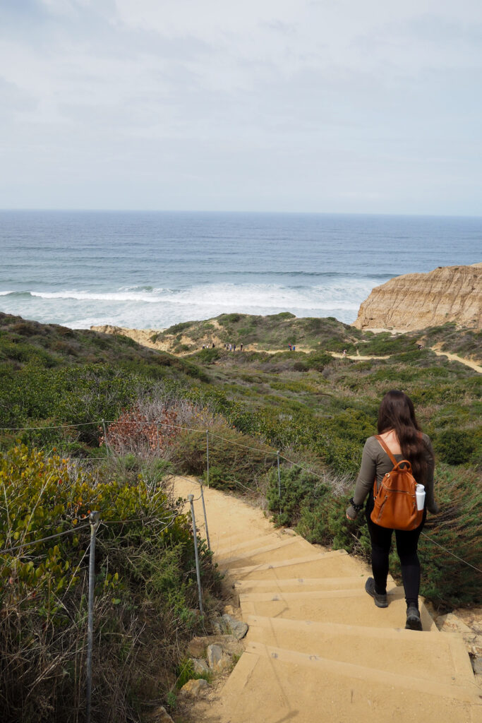 girl walking down stairs on a trail to the ocean