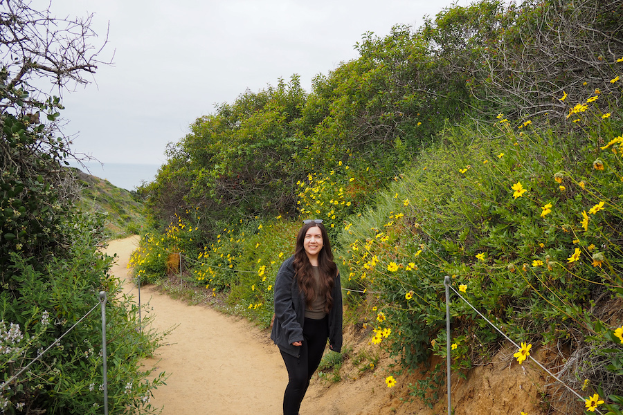 author, a young woman, on the guy fleming trail surrounded by wildflowers