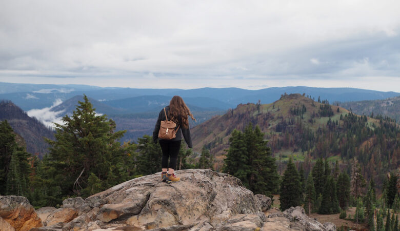 girl on a rock with views of mountains and trees in the background