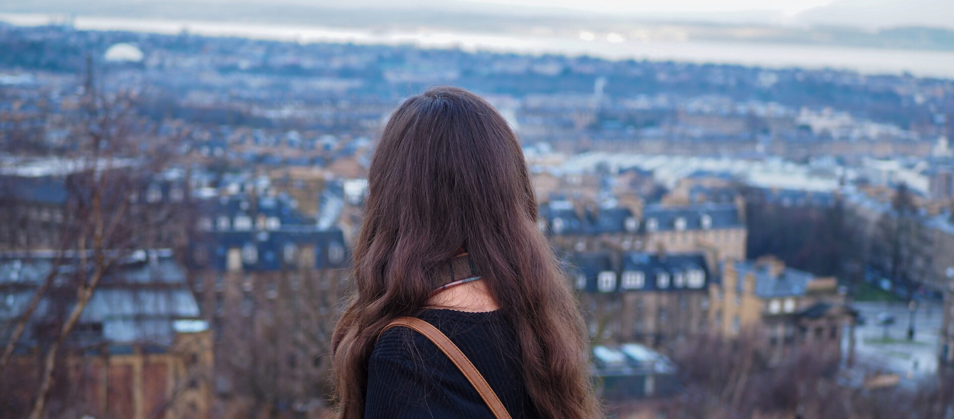 young woman looking out over new town edinburgh from calton hill