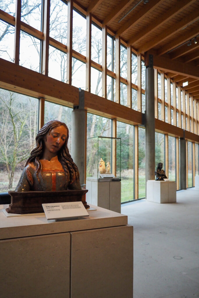 sculpture on display in museum the Burrell with large windows framing trees outside in the background