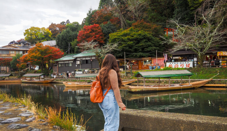 girl standing in front of a river with traditional boats in it