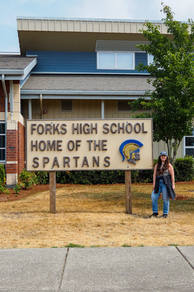 girl standing by the "Forks High School Home of the Spartans" sign
