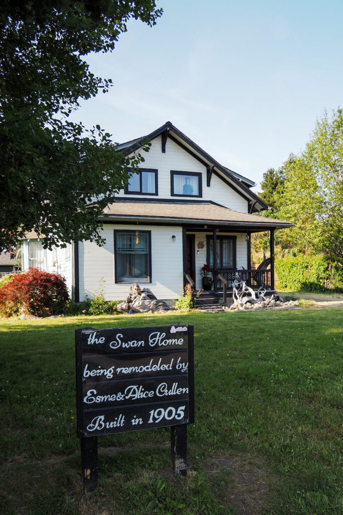 a house with a sign in front that says "the swan home being remodeled by Esme and Alice Cullen, built in 1905"