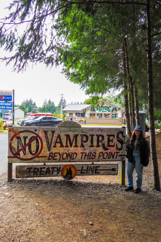 girl standing next to a sign that says "No Vampires Beyond This Point: Treaty Line"