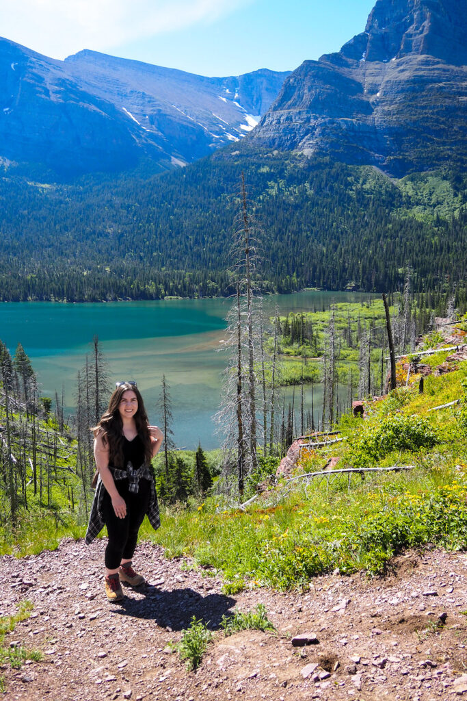 a woman on the trail to St Mary Falls with a lake and trees in the background in Glacier National Park