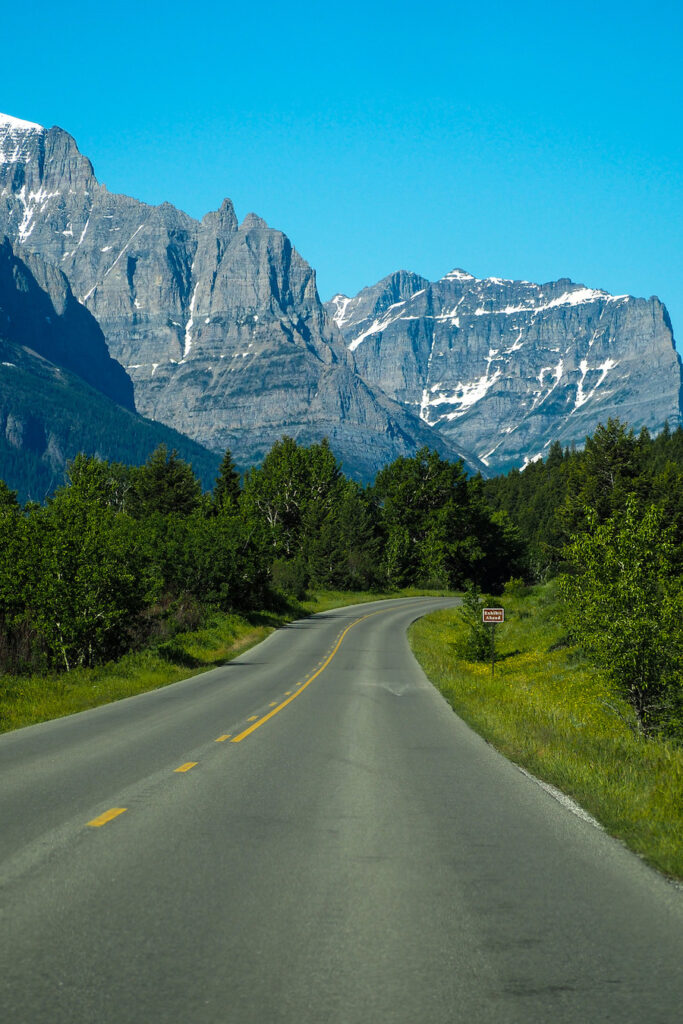 the road stretching forward, clear of cars, in Glacier National Park