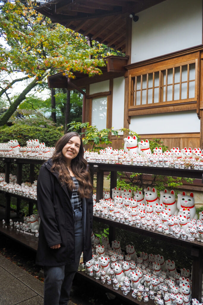 girl in front of shelves full of lucky cats
