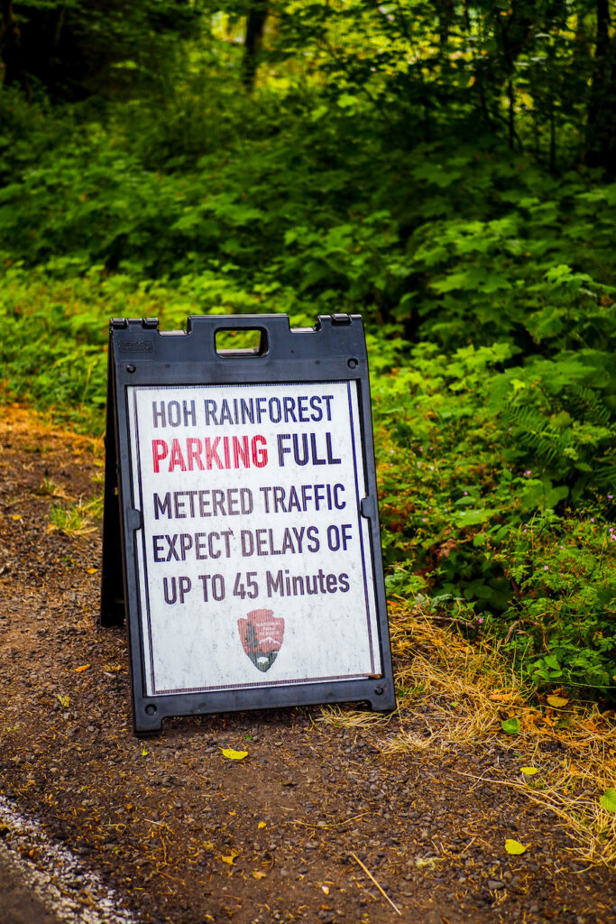 a sign on the side of the road that says "hoh rainforest parking full: metered traffic: expect delays up to 45 minutes"