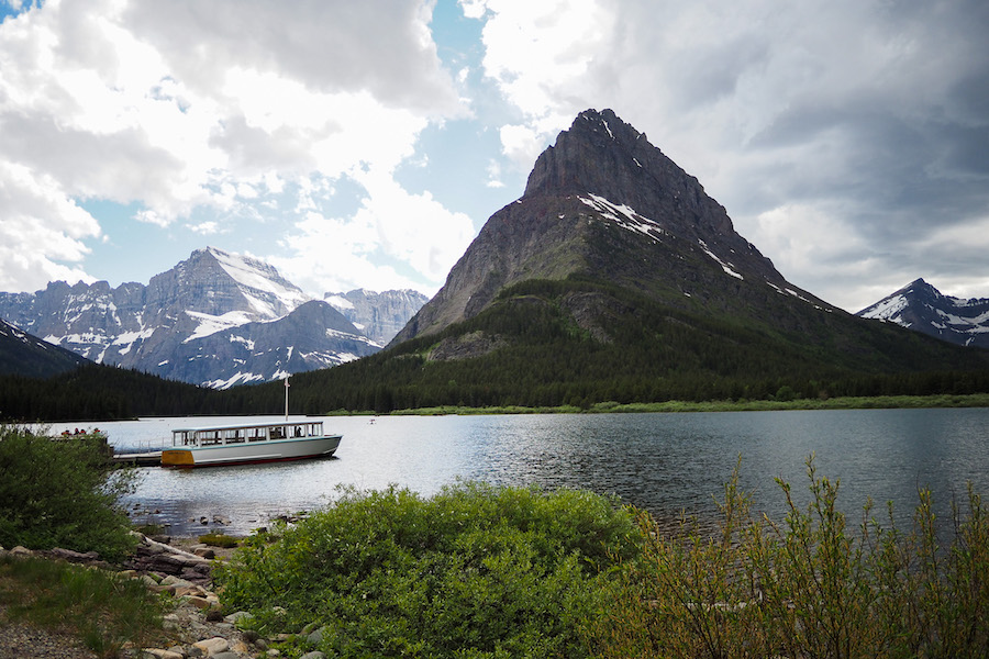 a boat sitting on the lake near a dock in Glacier National Park