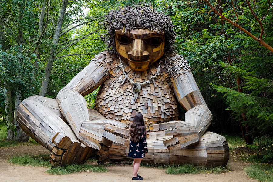 girl standing in front of a large wooden troll named Pia