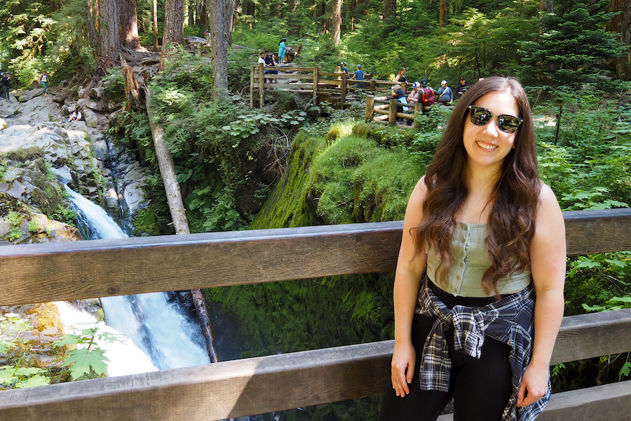 Girl standing on a wooden bridge with a waterfall just beyond