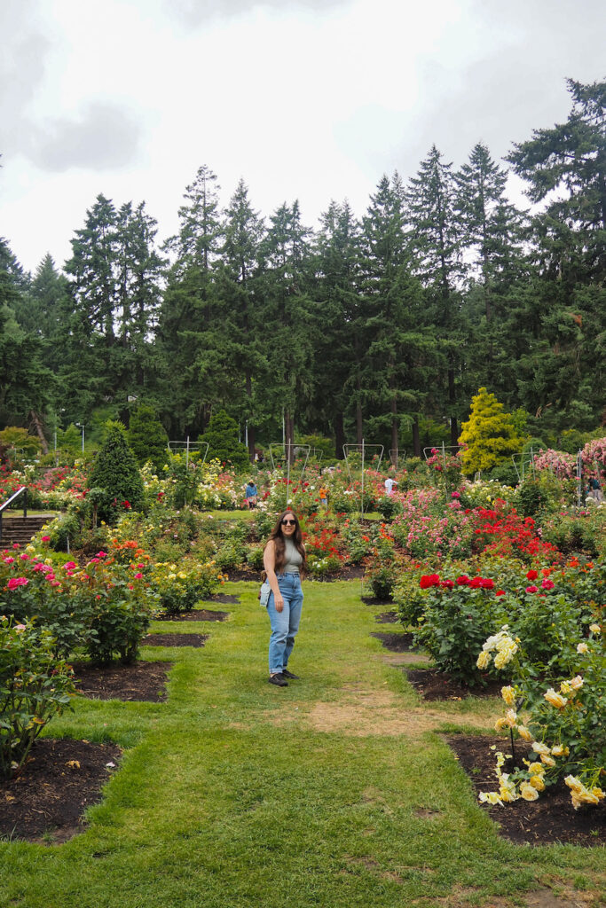 girl standing amid roses in the international test rose garden in Portland