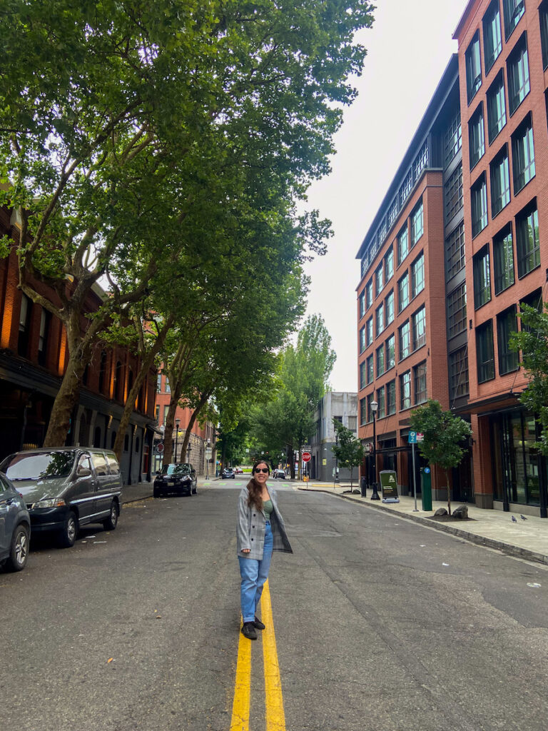 girl standing in the middle of a street in downtown Portland with no cars anywhere 