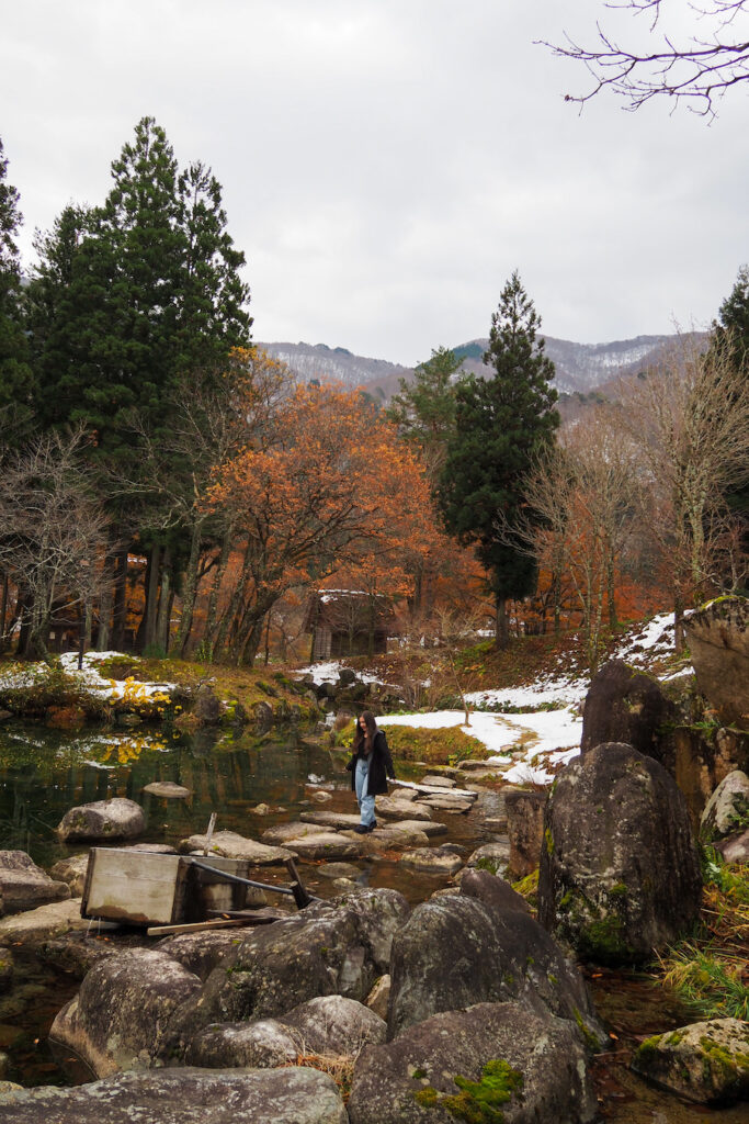 girl walking on stones through a pond in a garden