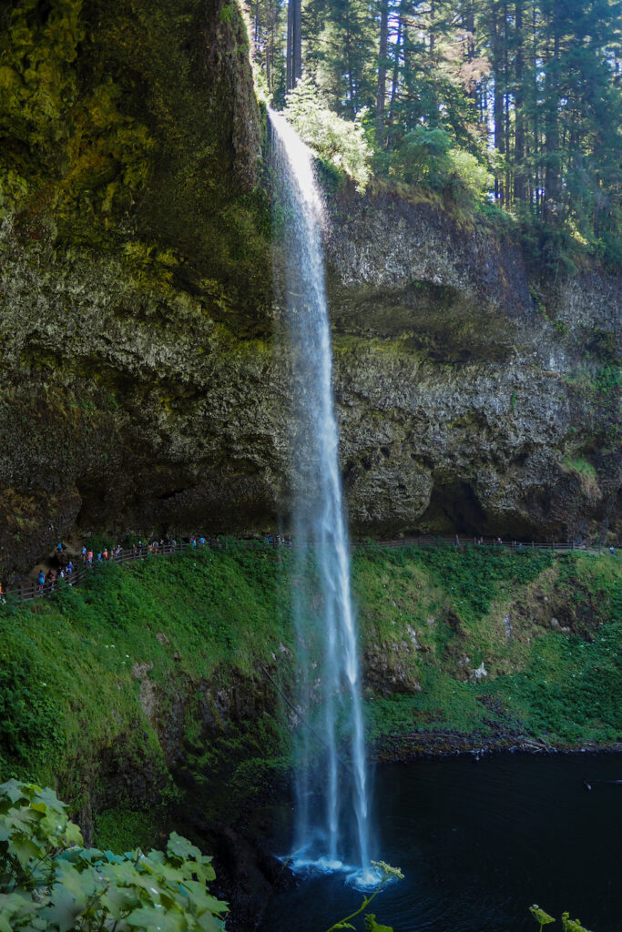 the South Falls waterfall with people walking behind it in Oregon
