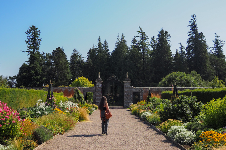 young woman standing on a path in a walled garden